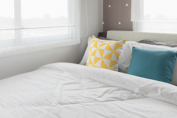 Fototapeta na wymiar colorful pillows on white bed in modern bedroom