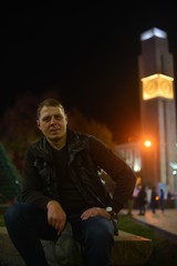 Photo outdoor of A man sits smiling against the background of the evening cityscape