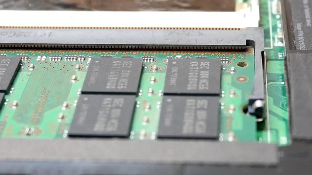 Hand in blue gloves installing ram memory dimm in notebook in the service center for repair and upgrade of computers or laptop