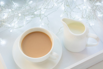 Christmas and winter concept. White mug of hot black coffee,milk jug  and garland in white birchbox. Top view.