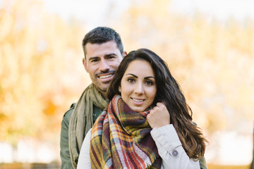Lovely cheerful young couple portrait in autumn at the park.