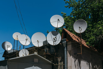 Many satellite dishes on the roof of the house.