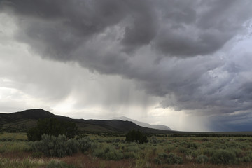 Scenic view of stormy clouds raining over landscape