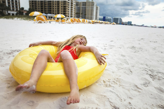 Full length of girl relaxing on inner tube at beach