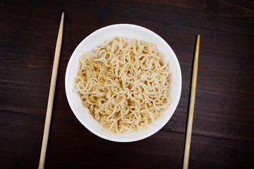 Chinese noodles fast food. Harmful food poor students. Beautiful still life on a dark wooden background.