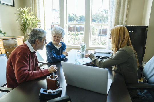 Financial advisor explaining plan to senior couple on tablet computer while sitting in office