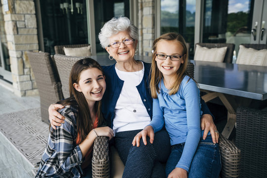 Portrait of grandmother with granddaughters sitting on porch