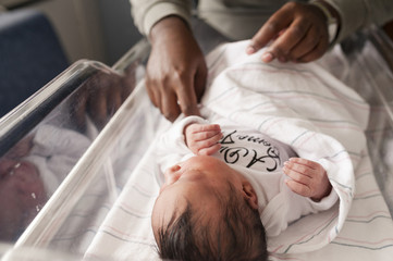Cropped image of person adjusting blanket of newborn baby