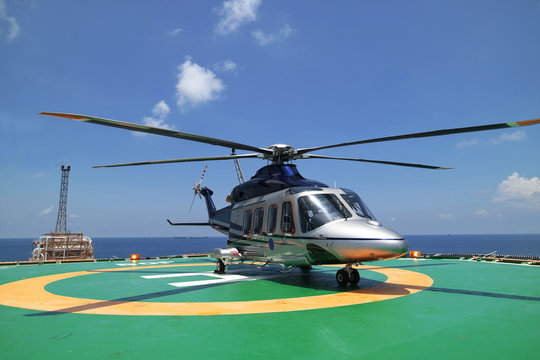 Helicopter or chopper land at oil and gas platform area for get and sent passenger from onshore hangar to offshore platform