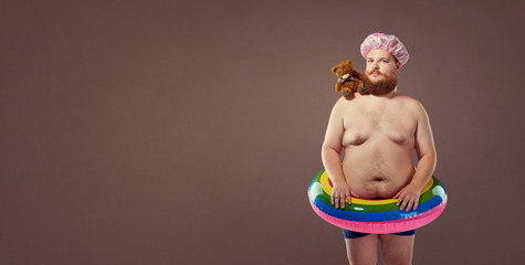 Funny fat bearded man in a swimsuit in for swimming inflatable ring.