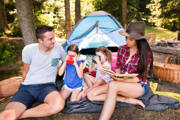 Beautiful young family with daughters camping in forest.