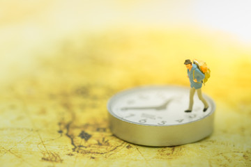Travel and time concept. Traveler miniature people figure walking on watch and on world map.