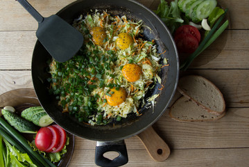 Fried eggs with vegetables in a pan