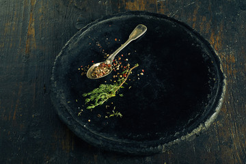 Teaspoon with herbs and rosemary on old plate