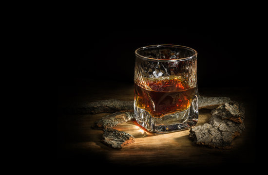 malt whiskey in a glass stands on a wooden board around oak chips