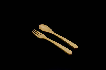 Wooden spoon and fork isolated on black background