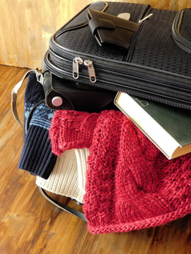 Suitcase full of clothes, book, camera and wallet for a trip. Travel concept