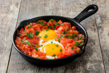 Shakshuka in iron frying pan on wooden table. Typical food in Israel.
