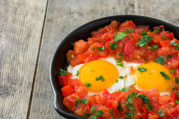 Shakshuka in iron frying pan on wooden table. Typical food in Israel.
