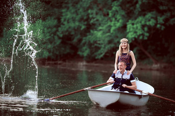 happy couple rowing and splashing on lake