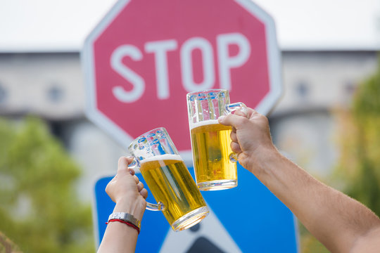 Toasting with beer in front of stop street sign