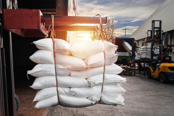 Forklift handling white sugar bags outside warehouse for stuffing into container for export
