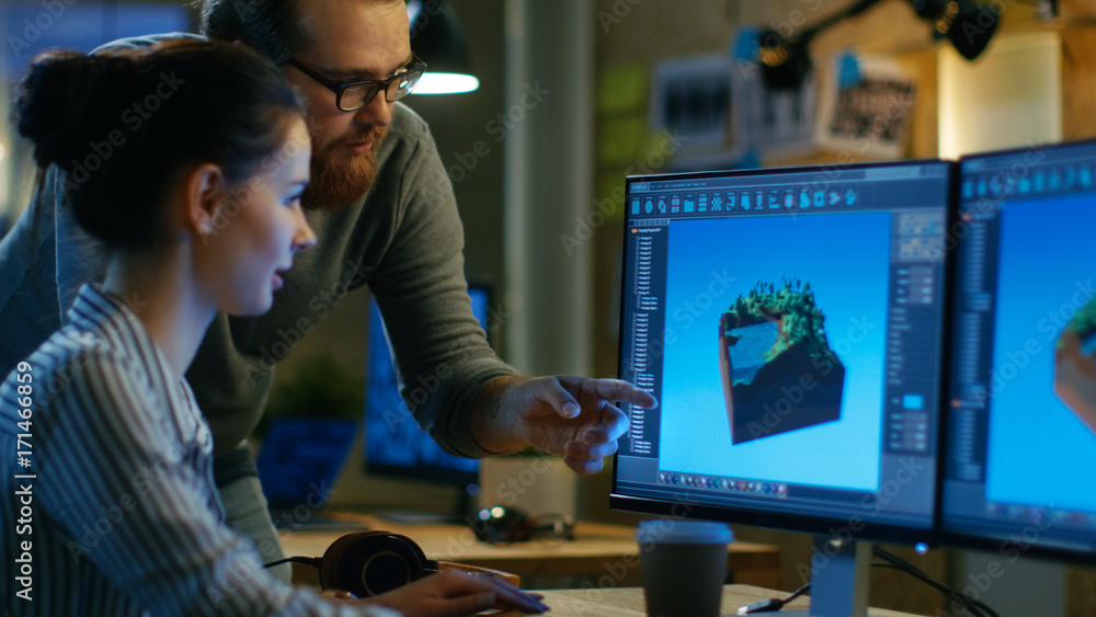 Poster Female Game Developer Has Discussion with Male Project Manager While Working on a Game Level on Her Personal Computer with Two Displays. They Work in a Modern Loft Office Creative Environment.