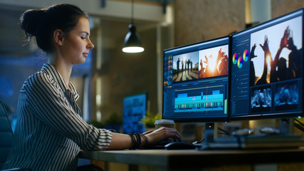 Female Video Editor Works with Footage and Sound on Her Personal Computer. She Works Late. Her...