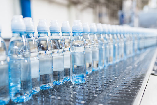Bottling plant - Water bottling line for processing and bottling pure spring water into blue bottles. Selective focus. 