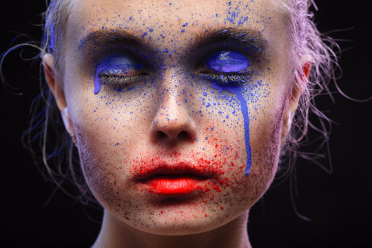 female portrait with creative multicolored makeup on black background