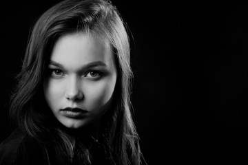 beautiful young sad woman in blouse at black background looking at camera, monochrome