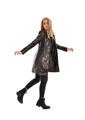 Fototapeta premium full length portrait of girl wearing black clothes and long leather jacket. standing pose in white background.
