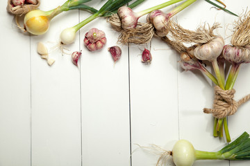 Fresh garlic and onions on a white wooden table.