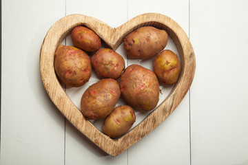 Yams and baking potatoes arranged on a painted wooden table top background to form a page border