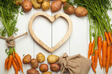 Fresh vegetables, potatoes and carrots against a white wooden background