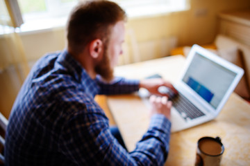 Obraz na płótnie Canvas blurred background, businessman using laptop at workplace - rear view