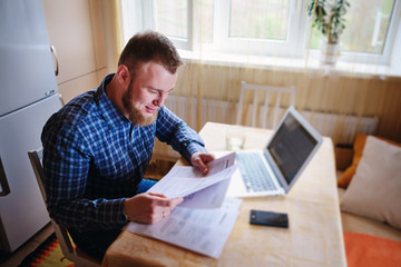 Handsome man doing some paperwork at home