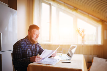 Businessman at home, he is working with a laptop, checking paperwork and bills