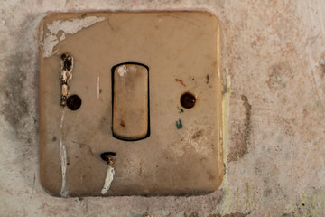 Old light switch with rusted screws on a white old wall