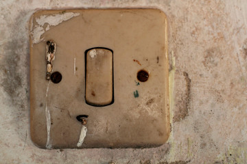 Old light switch with rusted screws on a white old wall