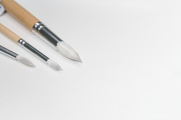 Three different white paint brushes on cork board