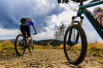 Fototapeta na wymiar Cycling women and man riding on bikes in autumn mountains forest landscape. Couple cycling MTB enduro flow trail track. Outdoor sport activity.