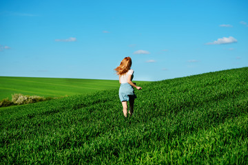 Fototapeta na wymiar Young beautiful woman running on a green field