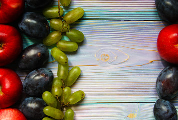 Apples, plums and grapes on a soft blue background