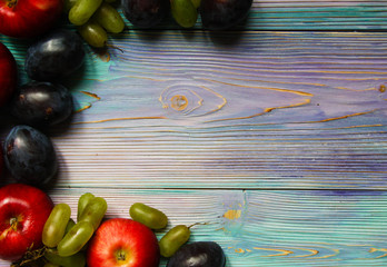 Apples, plums and grapes on a soft blue background