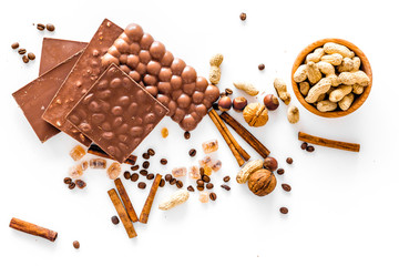 Preparing chocolate. Chocolate bars, nuts, cinnamon on white background top view