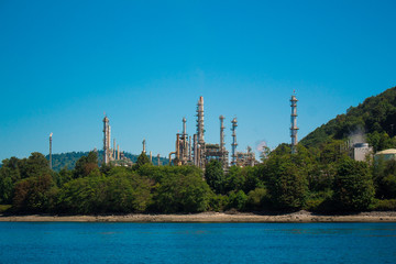 Photo of industrial site behind trees across water