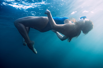 Fototapeta na wymiar Woman floating underwater in blue ocean