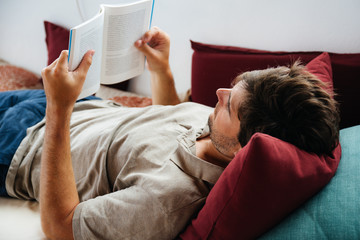 Man lying on the sofa and reading a book