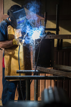 A man in a workshop using an industrial metal grinder to grind down stainless steel